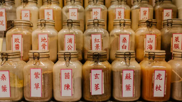 A variety of herbal medicine jars with Chinese labels displayed in a shop.