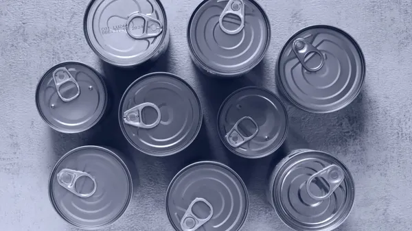 High-angle shot of canned food tins arranged on a rough surface, emphasizing texture and symmetry.