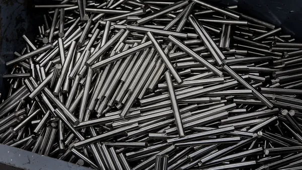 Close-up of numerous stainless steel rods in a container, showcasing industrial metal texture.