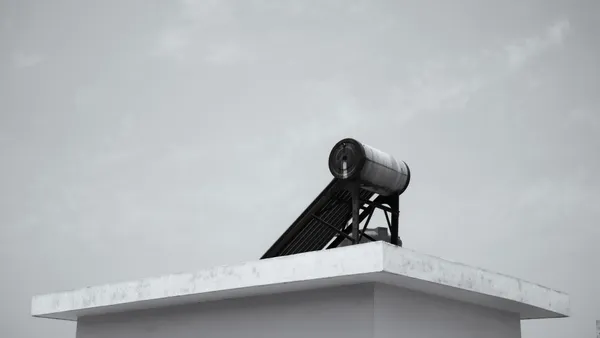 Solar water heater on a rooftop against a clear sky, energy efficient design.