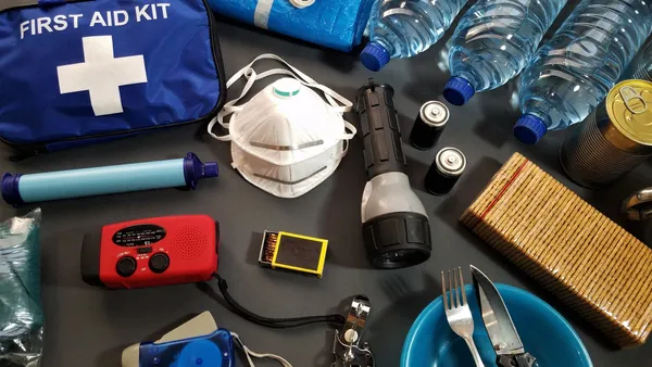 Flat lay of essential emergency survival kit items including first aid and water bottles.