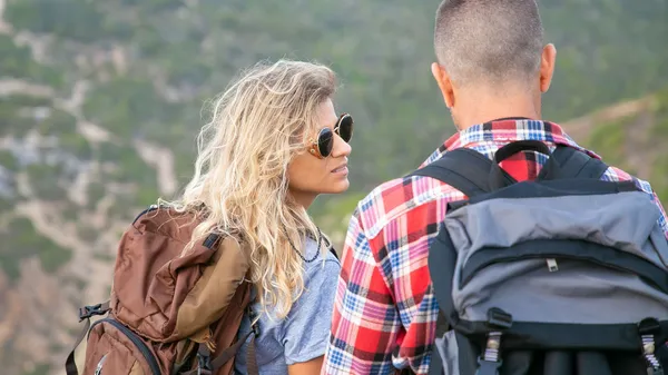 A young couple hiking in Portugal, enjoying the scenic outdoors with backpacks.
