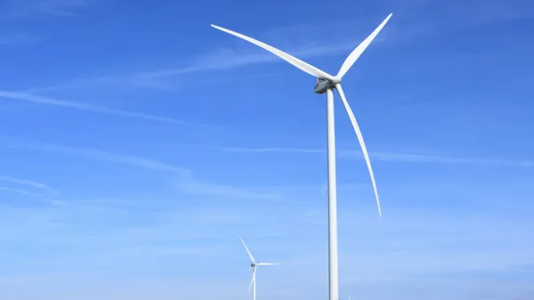 Wind turbines under a clear blue sky symbolize clean energy and sustainability.